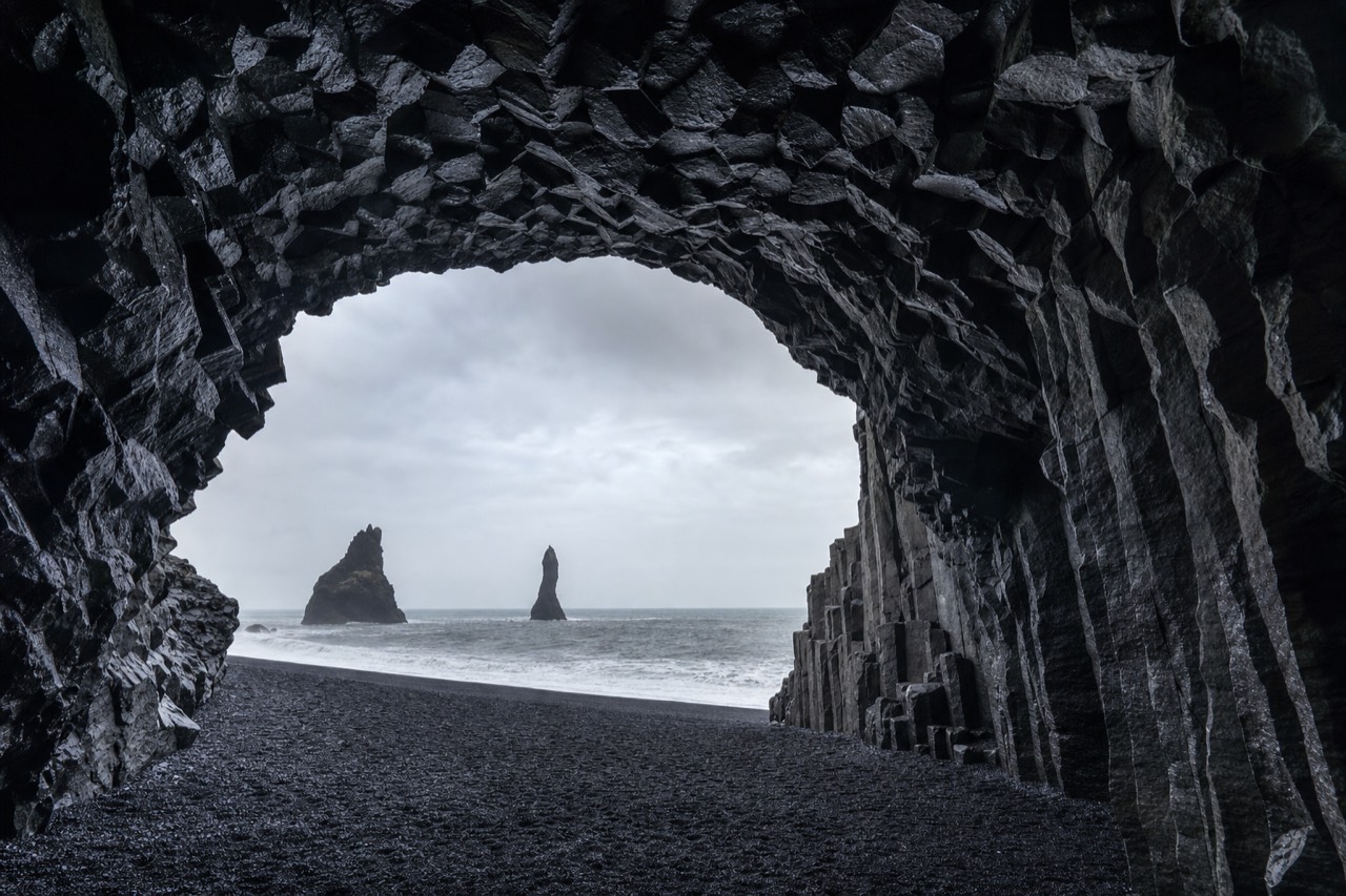 Looking out from the Halsanefshellir sea cave at Reynisfjara toward the Reynisdrangar sea stacks and black beach